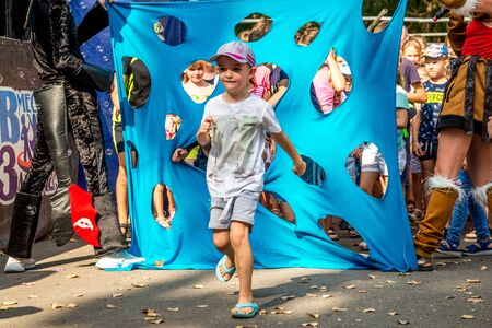 Volgodonsk, Russia-August 25, 2019: bubble show festival, art project ignite together. Holiday in the Park, children play in the competition, climb into the hole in the fabric and smile happilyのeditorial素材