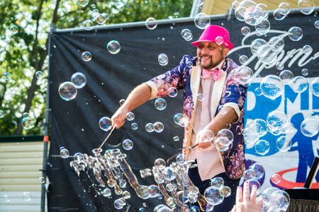 Volgodonsk, Russia-August 25, 2019: bubble show Festival, art project Ignite together. Young bright male artist release a lot of big bubbles from the stage. Audience children Teens happy and jubilantのeditorial素材