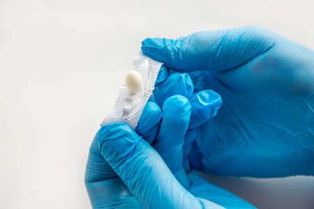 A gloved doctor opens suppositories for anal or vaginal use. Medical candles for the treatment of Candida, thrush, hemorrhoids, inflammation and fever. Effective drug on a white background. Copy spaceの写真素材