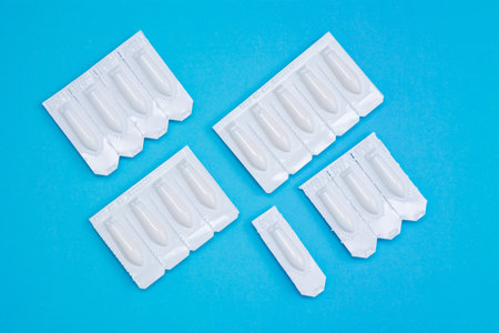 White suppositories for anal or vaginal use on blue background. Medical candles for treatment of...
