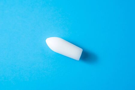 White suppositories for anal or vaginal use on blue background. Medical candles for treatment of Candida, thrush, hemorrhoids, inflammation and fever. Effective drug for timely treatment of diseasesの写真素材