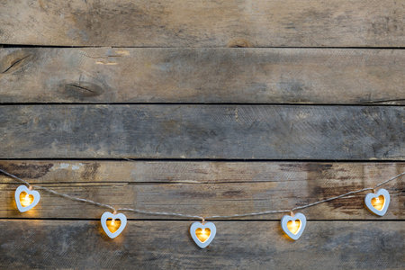 Old wooden background with a garland of white burning hearts. The concept of a Declaration of love,...