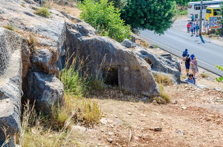 Limyra, Turkey June 11, 2018 Tourists on a tour of an ancient antique cemetery. The entrance to old concrete tomb in rock. historical monument of architecture. Burial of ancestors closer to the sky.のeditorial素材