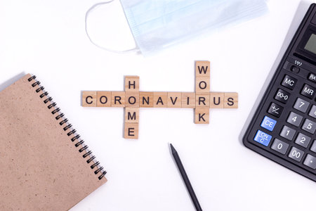 Text from wooden letters coronavirus work from home. Office supplies, a calculator, paper Notepad...