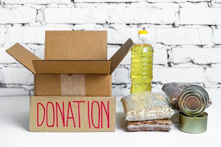 Food in cardboard donation box on a white background. Anti-crisis stock of essential goods for period of quarantine isolation.の写真素材