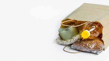 Banner. Food in a paper bag for donations, isolated on a white background. Anti-crisis stock of essential goods for period of quarantine isolation.の写真素材