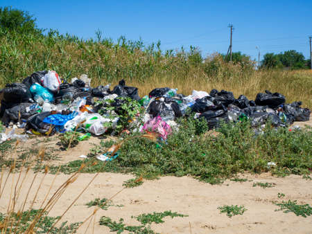 Dump on the river Bank. Garbage in nature. Lots of black bags of waste. Environmental problem of environmental pollution. Solid waste disposal in a big city. Volgodonsk, Russia 07 March 2020.のeditorial素材
