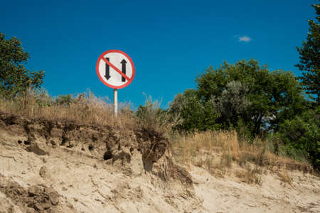 Banning coastal round navigation of the river sign. Divergence and overtaking are prohibited. Safety of navigation on inland waterways. A warning on a river on background of wild nature and the sky.の写真素材