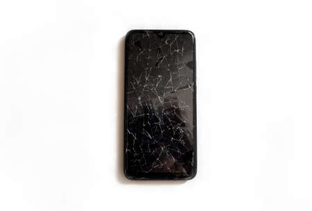 A modern mobile black touch smartphone with a broken glass screen isolated on a white background. Service, repair and technological concept. Copy space for text.の写真素材