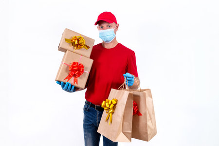 Safe contactless remote delivery of holiday gifts during coronavirus pandemic. A courier in red...