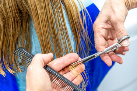 Home salon haircut during the quarantine. mature woman cuts long hair to young girl in bathroom....