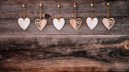 Valentines Day background. Brown old natural boards in grunge style with wooden decorative hearts. Copy space. Top view. Surface of table to shoot flat lay. Concept love, romantic relation. Banner.の写真素材