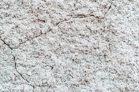 Concrete background. White old cracked stucco wall. Raised abstract texture. Damaged facade of building. Scuffed stone surface in grunge style. Table to shoot flat lay. Broken plaster. Copy space.の写真素材