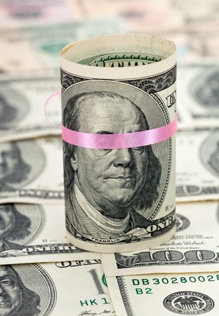 100 US dollar wrapped by ribbon on money backgroundの写真素材