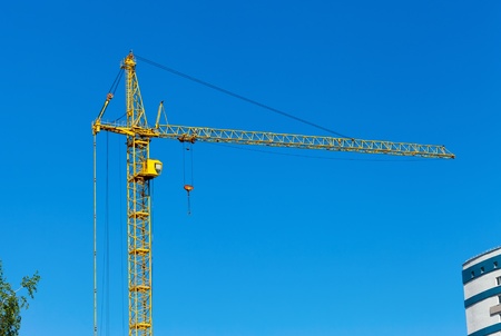 Yellow construction tower crane against blue skyの写真素材