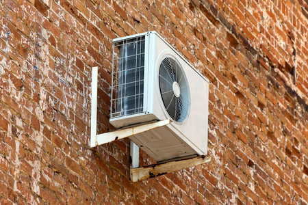 Air conditioning heat pump mounted on old brick wall 