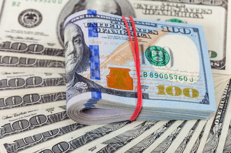 Folded dollar bills wrapped by rubber lying over  banknotes background