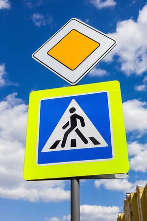 Traffic signs main road and pedestrian crossing with clouds in backgroundの写真素材