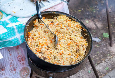 Cooking pilaf in a large cauldron outdoorsの写真素材