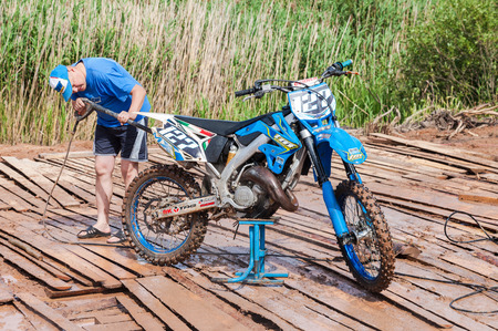 BOROVICHI, RUSSIA - JULY 11, 2015: Man washing a race bike after the competition in motocrossのeditorial素材