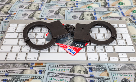 SAMARA, RUSSIA - JANUARY 9, 2016: Steel handcuffs and credit cards lying on a computer keyboard on the background of dollarsのeditorial素材