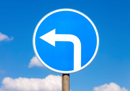Road sign Turn left against the blue sky