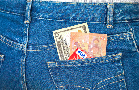 Ten american dollars, ten euro notes and credit cards sticking out of the blue jeans pocketのeditorial素材