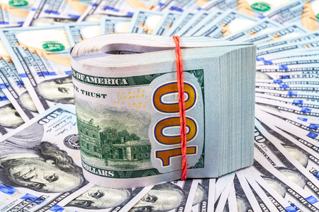 Folded dollar bills wrapped by rubber band over dollars banknotesの写真素材