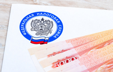 MOSCOW, RUSSIA - JANUARY 9, 2017: Tax payment notice letter with logo of the Federal Tax Service of Russia and ruble banknotes above. Tax payment conceptのeditorial素材