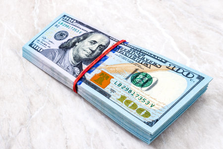 Stack of one hundred american dollar bills wrapped by rubber band