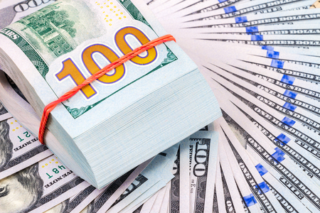 Folded dollar bills wrapped by rubber band over dollars banknotesの写真素材