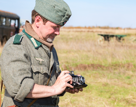 Samara, Russia - April 30, 2017: Unidentified member of Historical reenactment in German Army uniform with retro camera in summer dayのeditorial素材