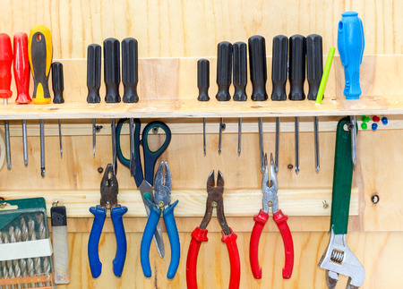 Different screwdrivers and pliers on a yellow chipboardの写真素材