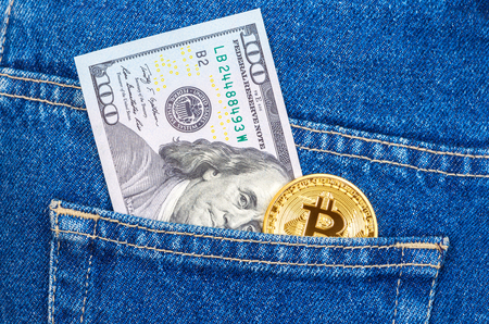 Banknote of one hundred american dollars and golden Bitcoin sticking out of the back jeans pocket. Business concept of digital cryptocurrencyの写真素材