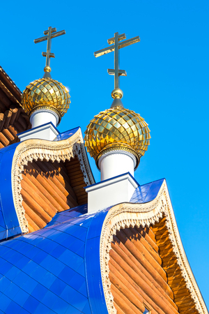 Golden domes with crosses on wooden orthodox church against the blue sky in Samara, Russiaの写真素材