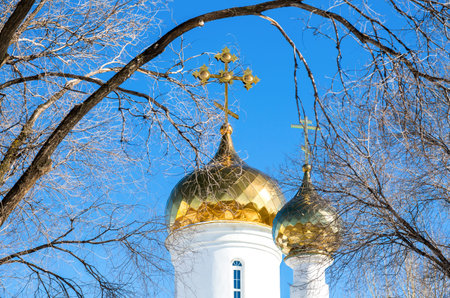 Domes of Russian orthodox church with golden cross against the blue sky in winter
