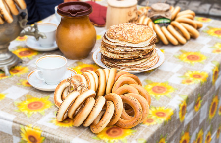 Tasty bagels, fried pancakes, samovar and tableware on the tableの写真素材