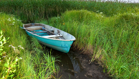 Old green plastic fishing boat at the lake in green grassの写真素材