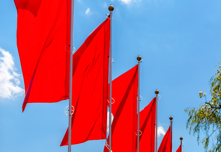 Red flags waving on the blue sky backgroundの写真素材