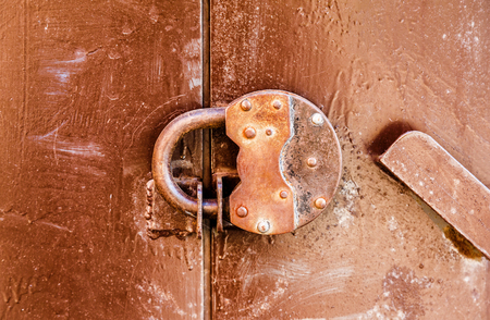 Rusty padlock on an old metal doorの写真素材