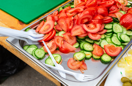 Sliced fresh tomatoes and cucumbers lie on a trayの写真素材