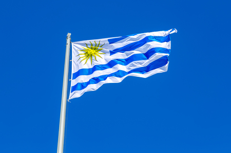 Flag of Uruguay waving in the wind against the blue skyの写真素材