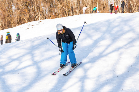 Samara, Russia - February 10, 2018: Young woman in sport gear learns to ride skiing in sunny winter dayのeditorial素材
