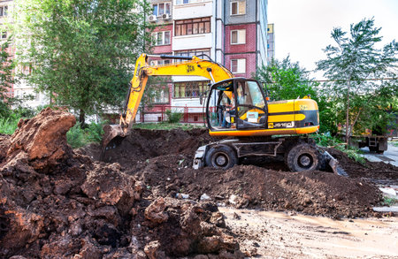 Samara, Russia - May 25, 2017: Yellow excavator digging a trench near the apartment building in...