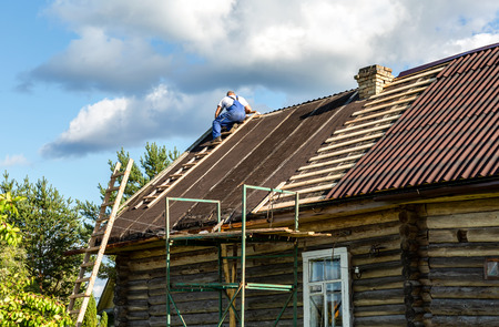 Novgorod, Russia - August 22, 2018: Worker repairs the roof of a wooden house in the villageのeditorial素材