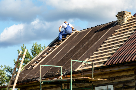 Novgorod, Russia - August 22, 2018: Worker repairs the roof of a wooden house in the villageのeditorial素材