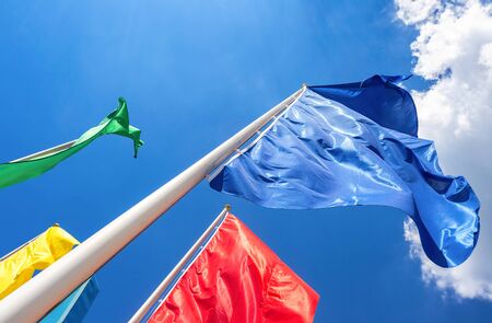 Colorful flags in the wind against the blue sky backgroundの写真素材