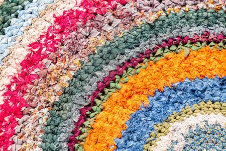 Old handicraft rug made from strips of cloth as background. Texture of a homespun doormat from different fabricsの写真素材