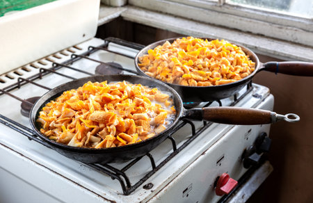 Mushrooms chanterelles are fried in an old cast-iron pan