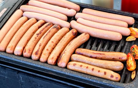 Appetizing sausages on a metal grid grilling over hot coals for a picnic lunchの写真素材